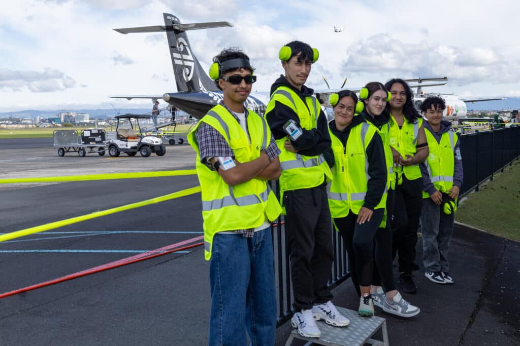 Six young adults standing outside small airport