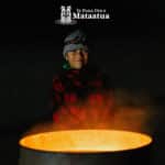 Young boy smiling in front of a bonfire