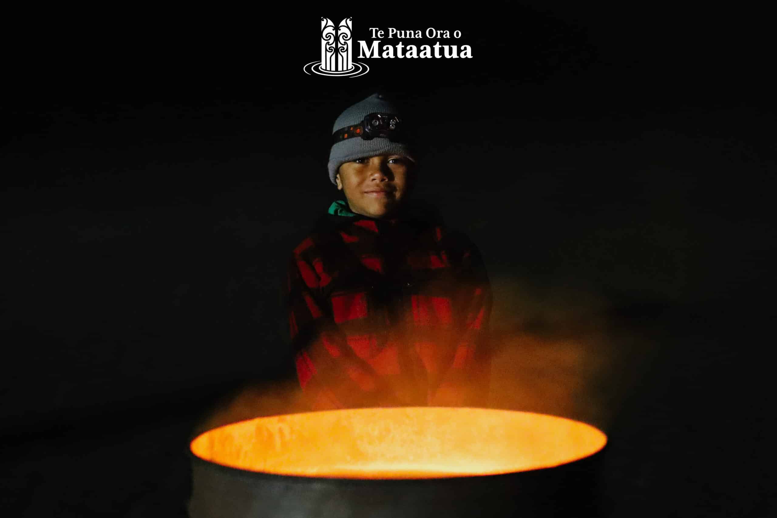 Young boy smiling in front of a bonfire