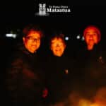 Three women huddled in front of a bonfire