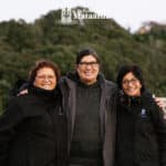 A group of people stand smiling against a backdrop of native bush