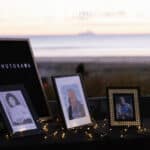 Three framed photos on a table. In the background is a pastel sunrise over a beach.