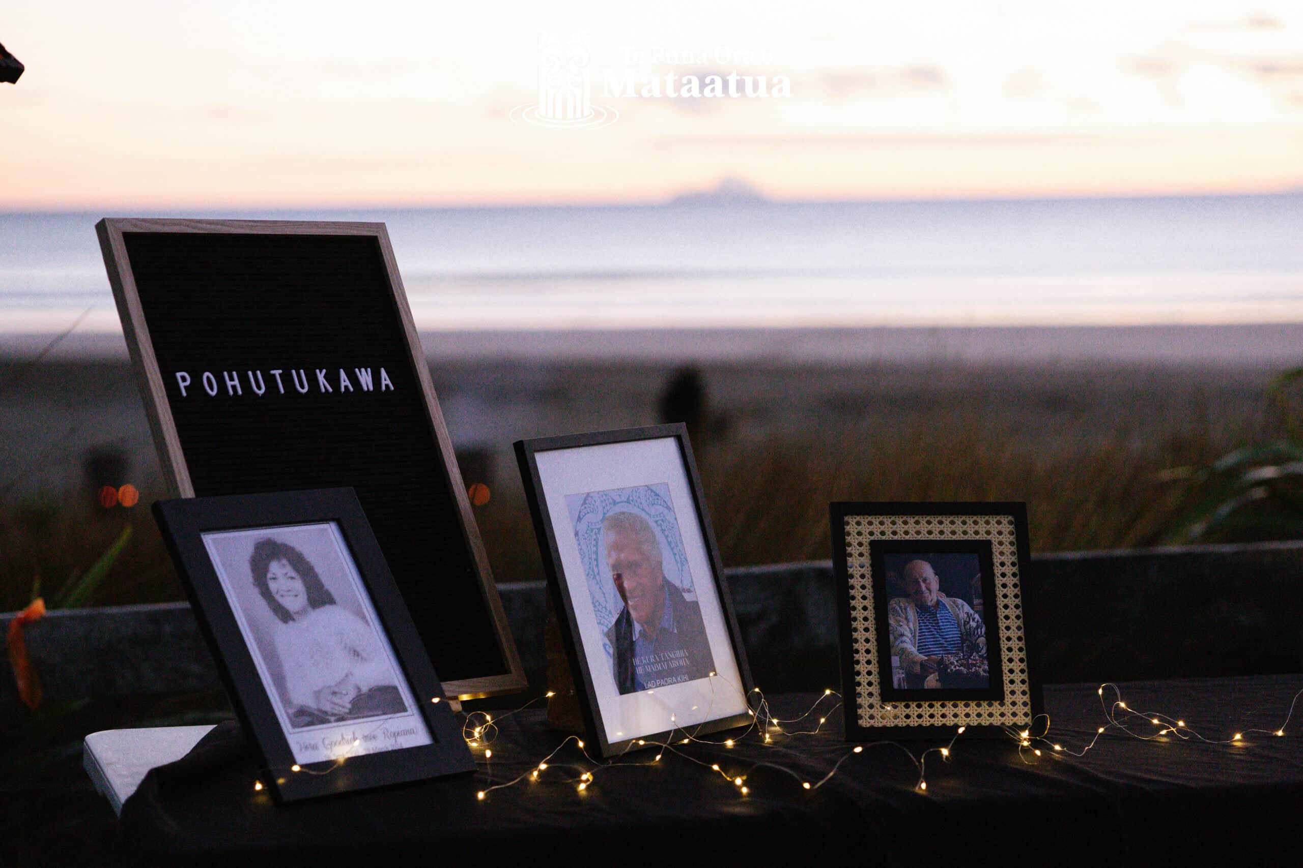 Three framed photos on a table. In the background is a pastel sunrise over a beach.