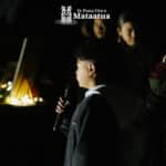 A group of children watch on as a small boy dressed in black gives a karakia/prayer