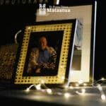 A photo of an elderly man is lightly lit by fairy lights